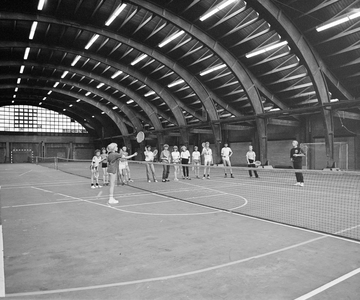 882637 Afbeelding van een tennisles die gegeven wordt in de oude veilinghal voor Groenten- en Vruchtenveilingen ...
